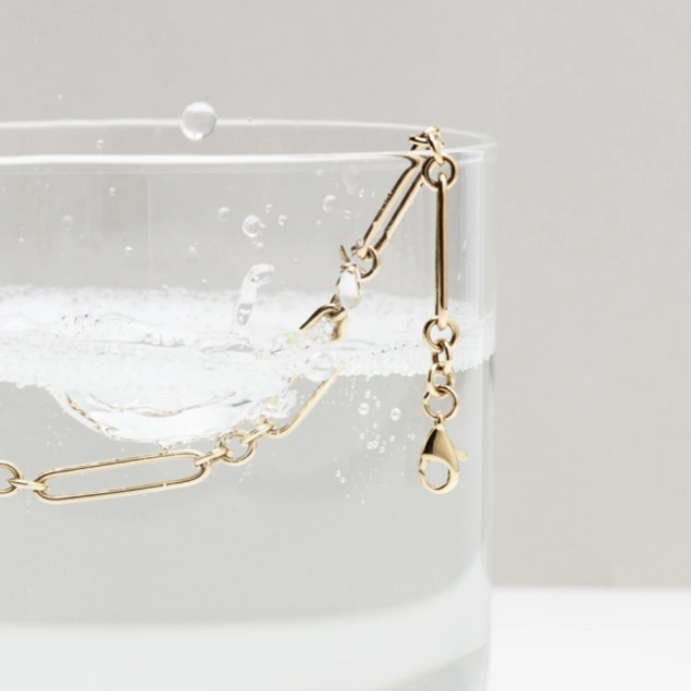 gold necklace chain in glass of soapy water